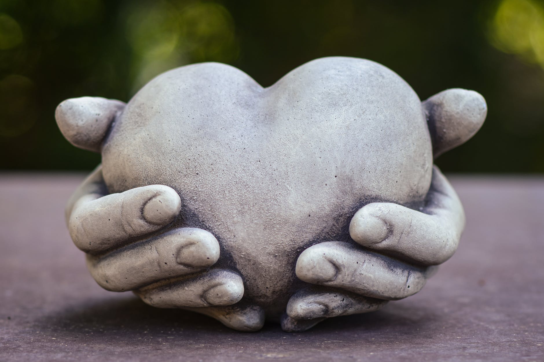 conceptual sculpture with hands holding a heart