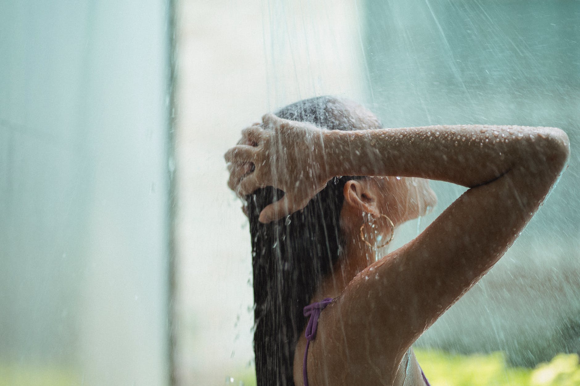 anonymous young woman washing hair under shower