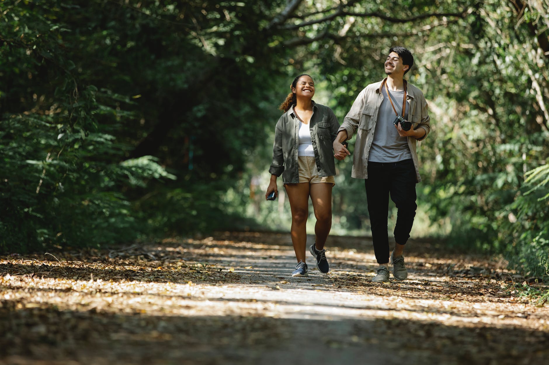 smiling diverse couple holding hands walking in park