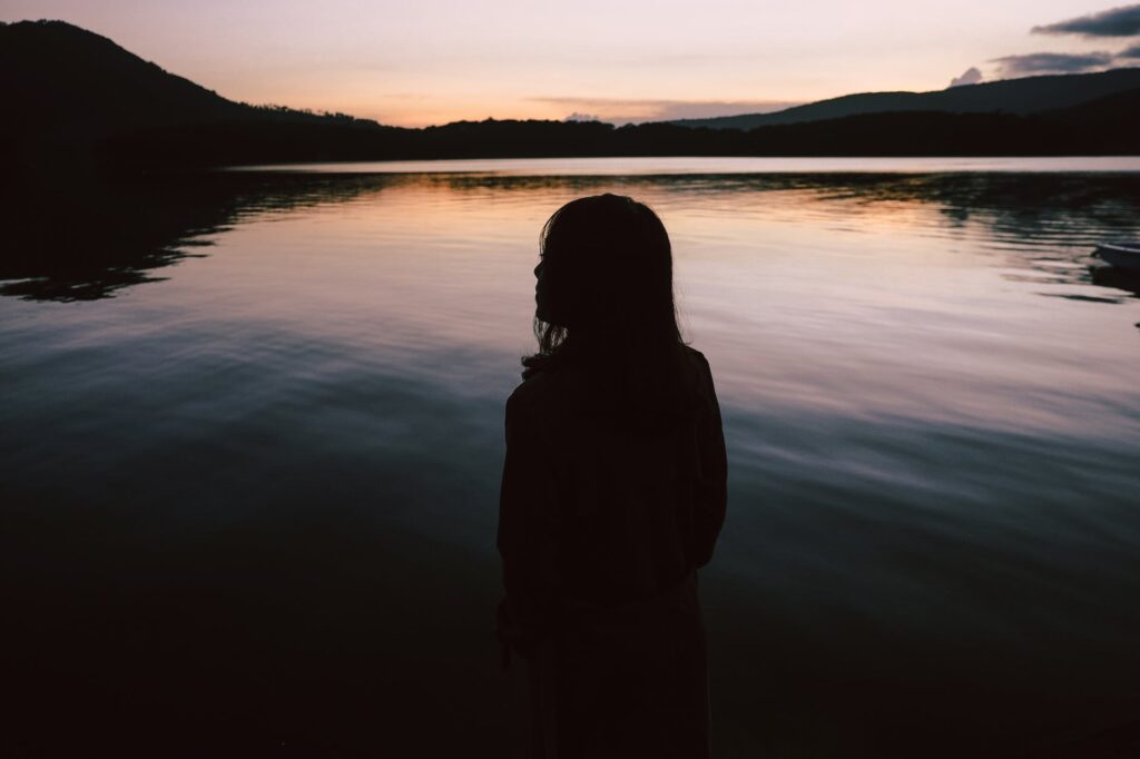 silhouette of woman standing near body of water