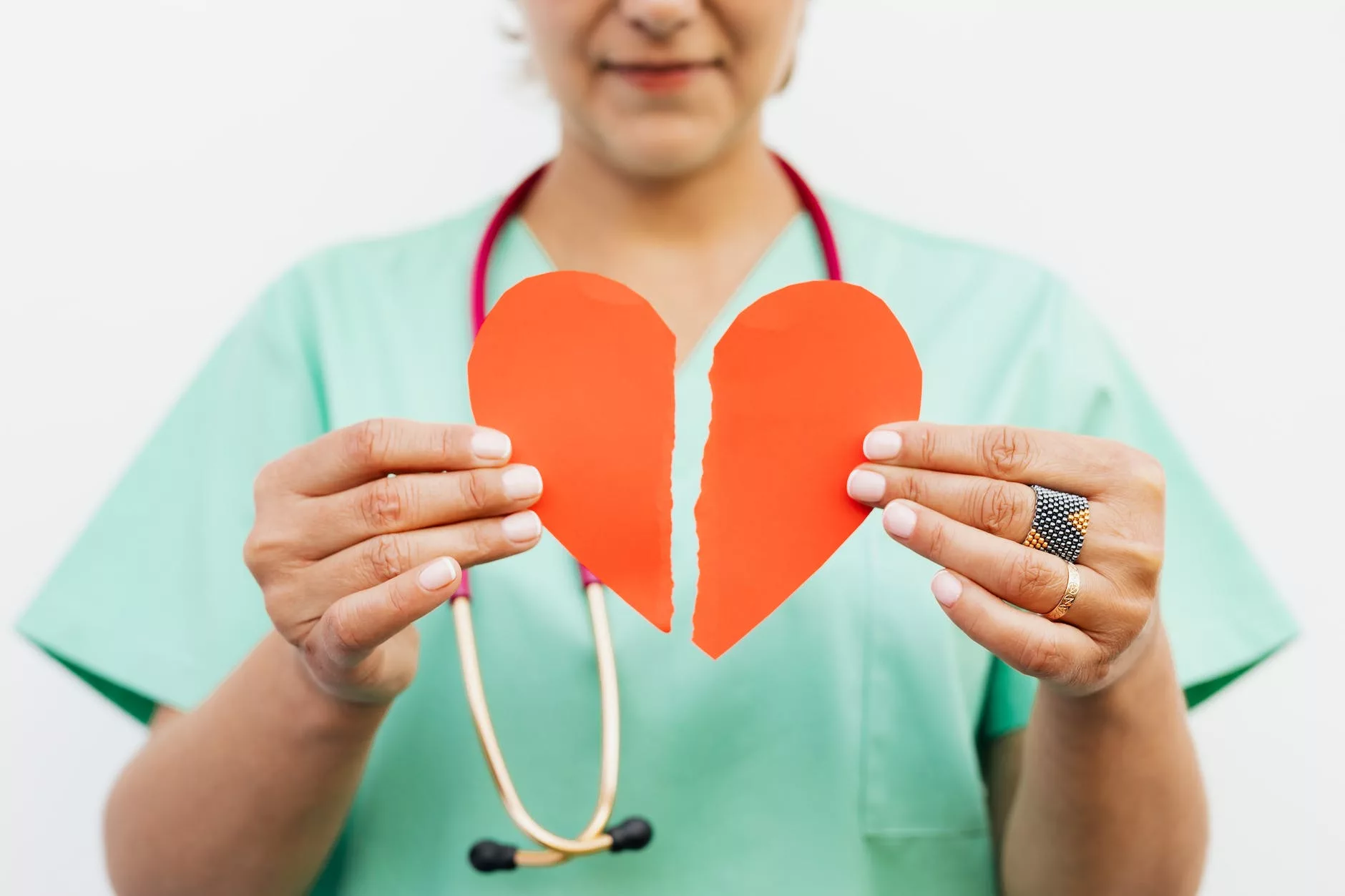 woman in teal scrub shirt holding heart shaped red paper