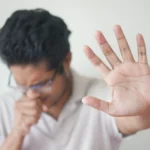 selective focus photo of coughing man s hand