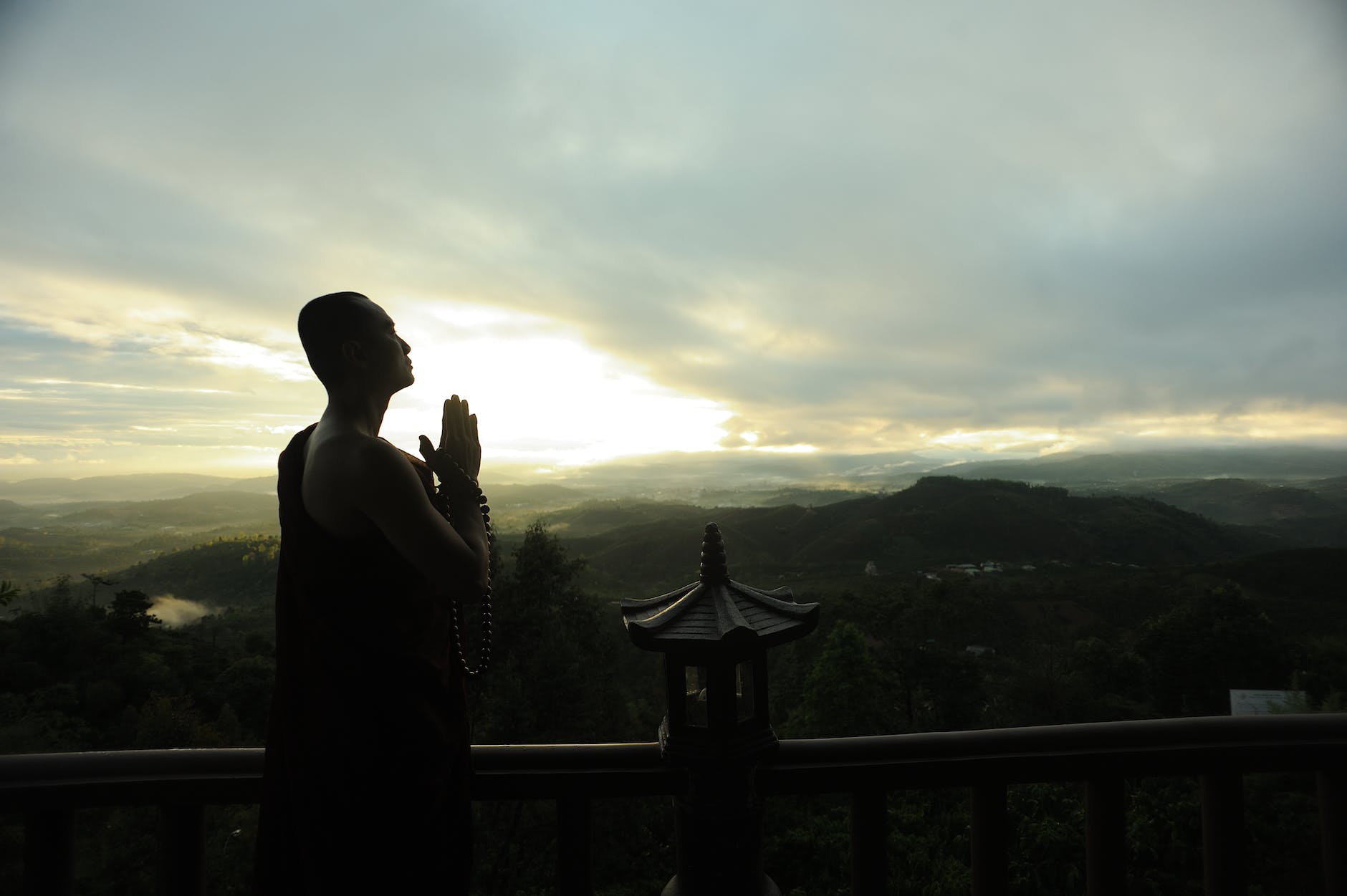 monk holding prayer beads across mountain